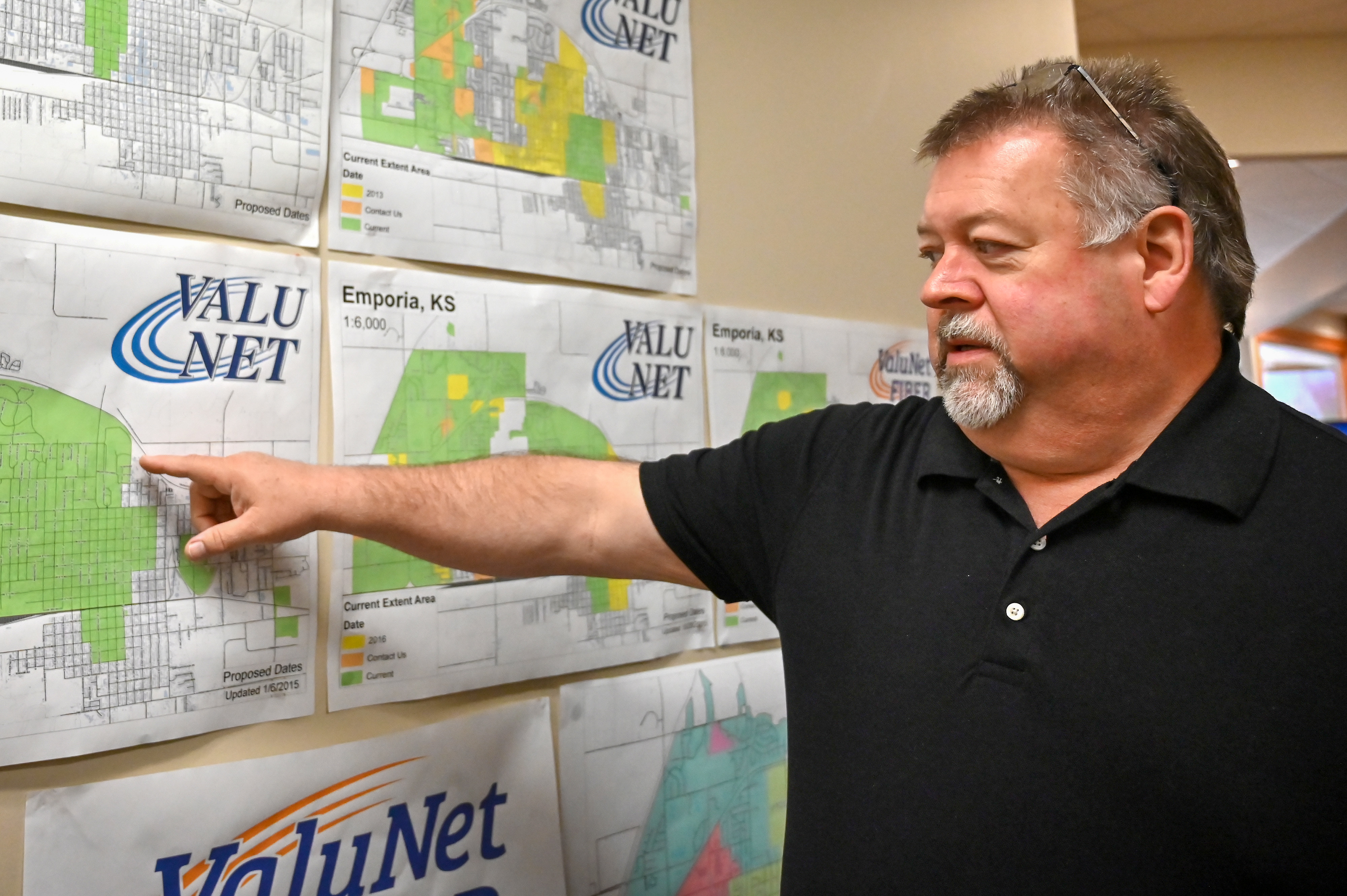 A ValuNet representative pointing to Emporia broadband coverage maps on a wall