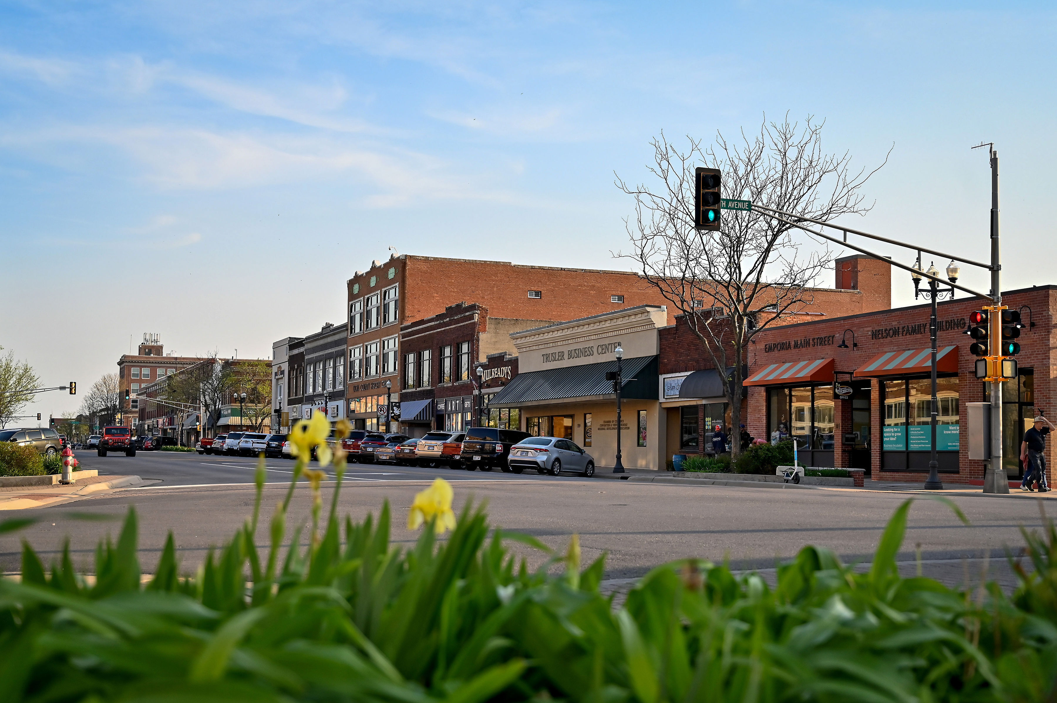 Downtown Emporia Main Street with historic brick storefronts and yellow irises in the foreground